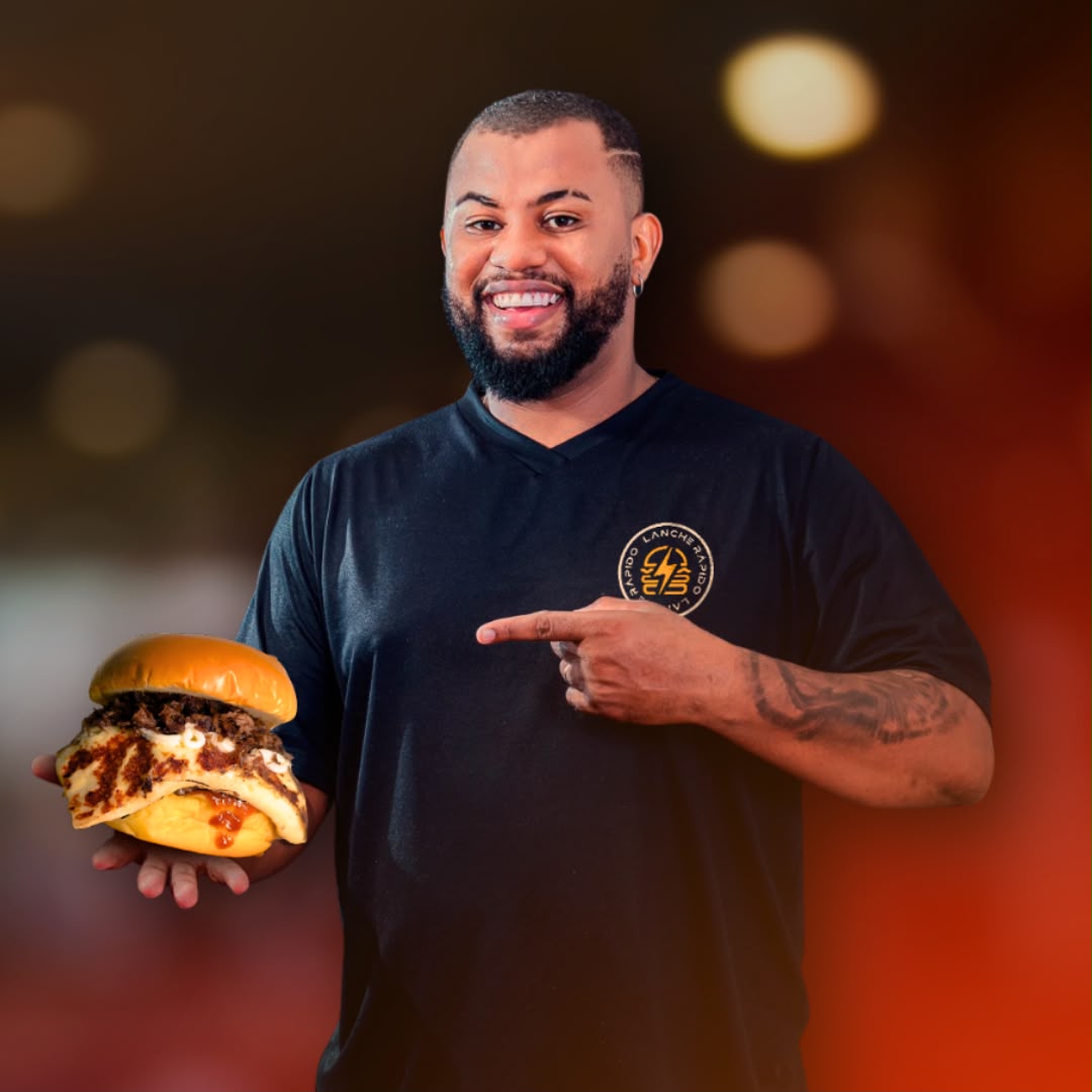 John Santos, dono da Lanche Rápido, segurando um hambúrguer